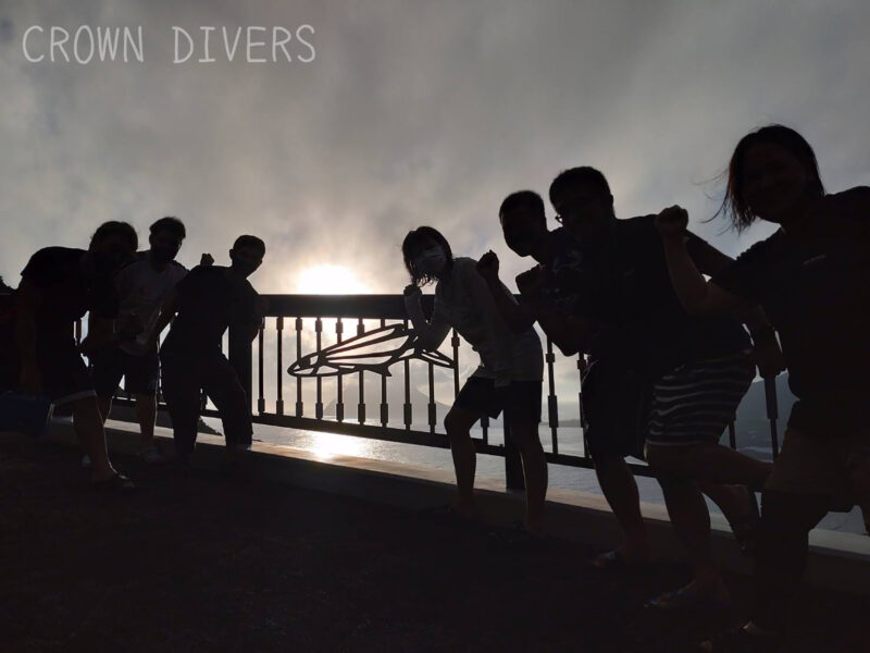 大坂トンネルの出口の橋の欄干で夕日をバックに記念写真を撮る人々