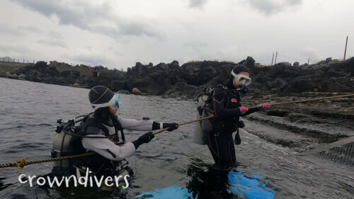 人生お初の体験ダイビングで水中に入っていくダイバーとインストラクター